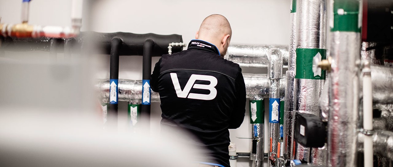 VB-rørlegger i arbeid med VB-logo på arbeidsklærne